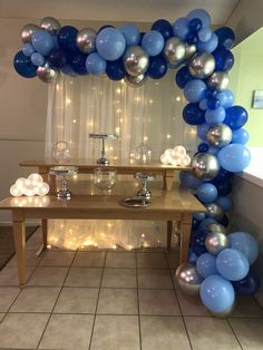 a table topped with blue and silver balloons