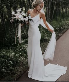 a woman in a white wedding dress is walking down the street with her arms outstretched