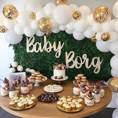 a table with desserts and balloons in front of a baby boy sign on the wall