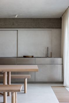 a table and benches in a room with concrete walls