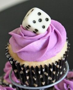 a cupcake with purple frosting and a dice on top