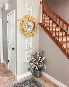 a welcome home sign hanging on the wall next to a potted plant and door