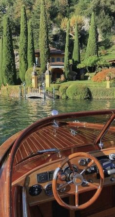 the steering wheel and dashboard of a boat on water with lots of trees in the background