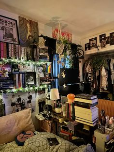 a cluttered bedroom with lots of books on the shelves and pictures hanging from the ceiling