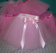 pink tutu skirt with white ribbon on the waist and bottom, sitting on top of a cutting board