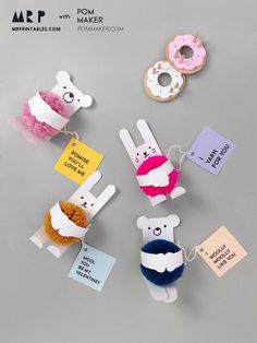 paper cut out animals with tags attached to them on a gray surface next to doughnuts and donuts