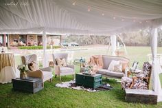 an outdoor area with couches, chairs and tables under a white tent on the grass