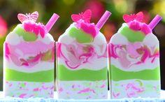 three soap bars with pink, green and white designs on them sitting on a table