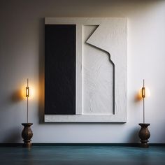 an abstract painting hangs on the wall next to two candle holders in front of it