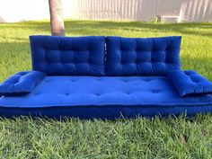 a blue futon couch sitting in the grass