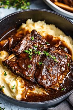 some meat and mashed potatoes in a skillet with gravy on top