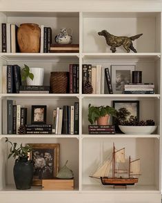 a book shelf with books, vases and pictures on it