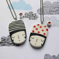 two necklaces with designs on them sitting next to each other