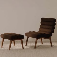 a chair and ottoman sitting next to each other on a carpeted floor in front of a white wall