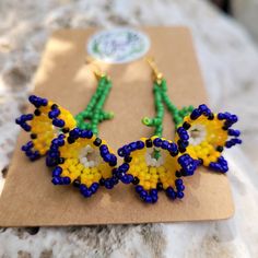 two pairs of colorful beaded earrings sitting on top of a piece of cardboard paper