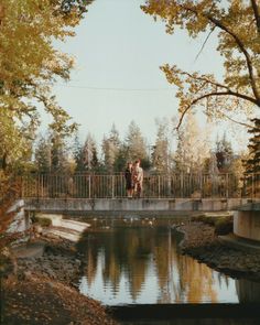 two people walking across a bridge over a river