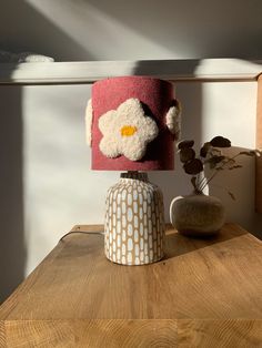 a lamp that is on top of a table next to a vase with flowers in it