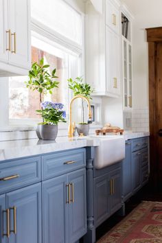 a kitchen with blue cabinets and white counter tops, gold handles on the faucet