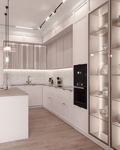 a modern kitchen with white cabinets and wood flooring is lit by recessed lights