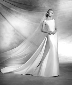 a woman in a wedding dress with a veil on her head, posing for the camera