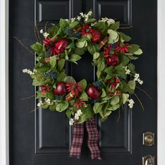 a wreath on the front door with pomegranates and greenery around it