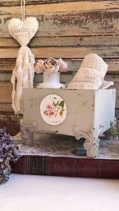 an old dresser is decorated with shabby decor and some flowers on the shelf next to it