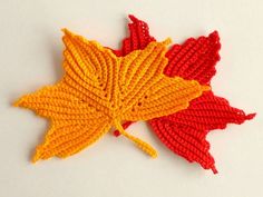 two crocheted autumn leaves laying on top of each other in red, yellow and orange