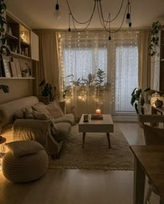 a living room filled with furniture next to a window covered in curtains and string lights