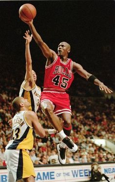 a basketball player jumping up to dunk the ball in front of two other players