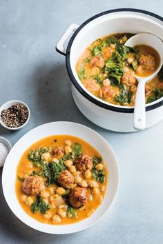 two bowls of soup with meatballs and spinach in them on a gray surface