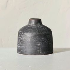 a gray vase sitting on top of a white table