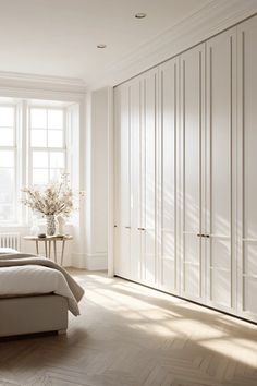 a bedroom with white walls and flooring next to a bed in front of a window