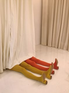 three pairs of yellow and orange tights laying on the floor in front of curtains