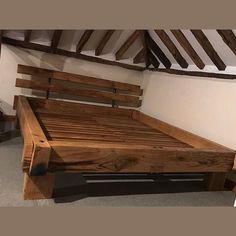 a bed frame made out of wood in a room with exposed rafters on the ceiling