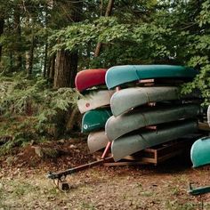 there are many canoes stacked on top of each other in the woods and ready to be used