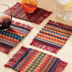 three place mats with fringes and a glass of wine on the table next to them