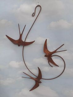 three metal birds flying in the sky with hooks attached to it's backs and wings