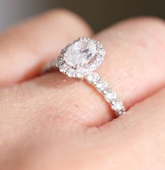 a close up of a person's hand with a diamond ring on their finger