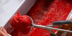 a person is scooping raspberry sauce into a pan