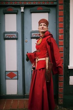 a woman in a red dress standing next to a blue door