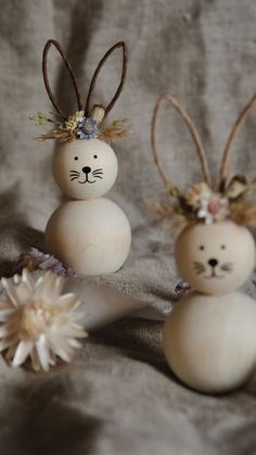 two bunny bunnies sitting on top of a bed next to each other with flowers in their ears