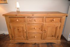 a wooden dresser sitting on top of a hard wood floor next to a white wall