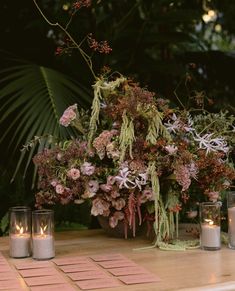 flowers and candles on a table in front of plants