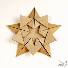 an origami star made out of brown paper on a white surface with black lines