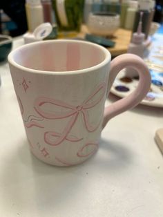 a pink coffee cup sitting on top of a table next to other crafting supplies