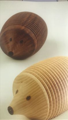 two wooden hedgehogs sitting next to each other on top of a white surface