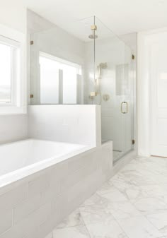 a white bathroom with marble flooring and large bathtub next to a walk in shower