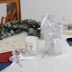 two white candles sitting on top of a table next to a box with a candle in it