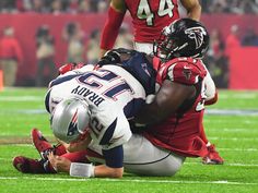 a football player is being tackled by another player on the field in front of an audience