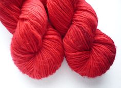 two skeins of red yarn on a white surface